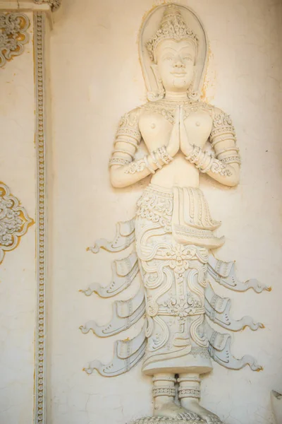 Cement angel craved in act paying respect to welcome to the public Buddhist temple. Thai style crafted stucco angel is acting Wai or Sawasdee. Sawasdee is the word to use for greetings and goodbye.