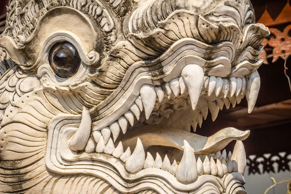 Close up white naga heads open mouth with white fangs in Thai\'s style patterned in Buddhist temple. Scary white head of the serpent statue that see the details of the eyes, and the white sharp teeth.