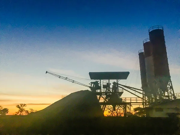 Silhouette concrete mixing plant with silos and dramatic sky background in the morning. Cement mixing silos, Stationary concrete batching plant, ready mixed concrete and construction facility concept.