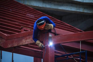 Tırmanma ve çelik çatı yapısı üzerine kaynak binaya çalışırken riskli kaynakçı inşaat alanında. Vasıflı işçi yüksek çelik yapı inşaat projesi üzerinde kaynak.