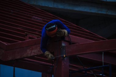 Tırmanma ve çelik çatı yapısı üzerine kaynak binaya çalışırken riskli kaynakçı inşaat alanında. Vasıflı işçi yüksek çelik yapı inşaat projesi üzerinde kaynak.