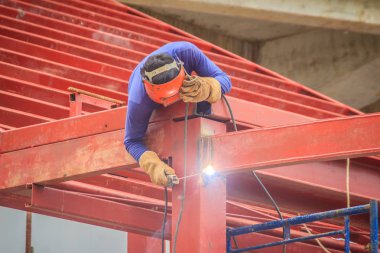 Tırmanma ve çelik çatı yapısı üzerine kaynak binaya çalışırken riskli kaynakçı inşaat alanında. Vasıflı işçi yüksek çelik yapı inşaat projesi üzerinde kaynak.