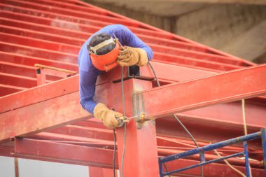 Tırmanma ve çelik çatı yapısı üzerine kaynak binaya çalışırken riskli kaynakçı inşaat alanında. Vasıflı işçi yüksek çelik yapı inşaat projesi üzerinde kaynak.