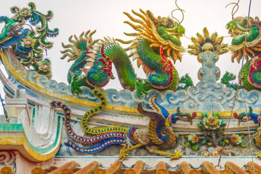 Güzel büyük yüz buruşturma ejderha Çin tapınaklarda dekoratif kiremit çatı üzerinde sürünerek. Geleneksel Çince Tapınağı ile ejderha heykeli mavi gökyüzü arka plan üzerinde renkli çatı detay. Seçici odak.