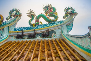 Güzel büyük yüz buruşturma ejderha Çin tapınaklarda dekoratif kiremit çatı üzerinde sürünerek. Geleneksel Çince Tapınağı ile ejderha heykeli mavi gökyüzü arka plan üzerinde renkli çatı detay. Seçici odak.