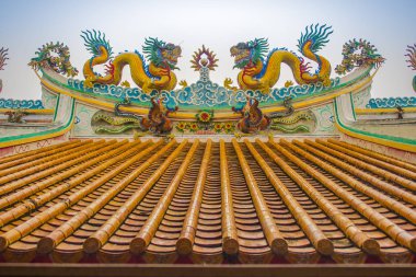 Güzel büyük yüz buruşturma ejderha Çin tapınaklarda dekoratif kiremit çatı üzerinde sürünerek. Geleneksel Çince Tapınağı ile ejderha heykeli mavi gökyüzü arka plan üzerinde renkli çatı detay. Seçici odak.