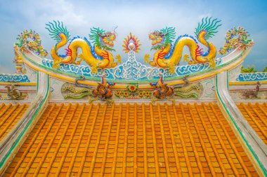 Güzel büyük yüz buruşturma ejderha Çin tapınaklarda dekoratif kiremit çatı üzerinde sürünerek. Geleneksel Çince Tapınağı ile ejderha heykeli mavi gökyüzü arka plan üzerinde renkli çatı detay. Seçici odak.