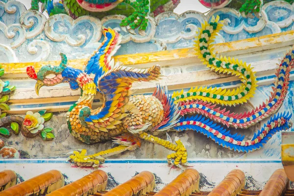 中国の寺院で装飾的なタイル屋根の上を飛んでいるカラフルなフェニックス鳥 伝統的な中国の寺院の美しい屋根詳細 — ストック写真