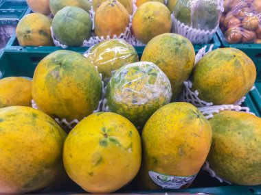 Süpermarkette satılık koruma köpüğüyle sarılı taze organik olgun papaya..