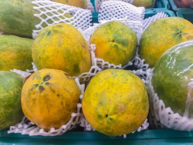 Süpermarkette satılık koruma köpüğüyle sarılı taze organik olgun papaya..