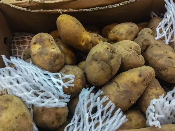 Organic raw potatoes for sale in the supermarket stand. Pile of potatoes in the food market for background.