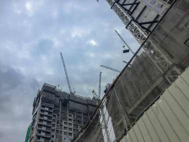 Yüksek binaların inşaat projesinde yelken yelkenli vinç. Gökdelen inşaatı devam ediyor. Gökyüzü arka planının altında kule vinçleri var..