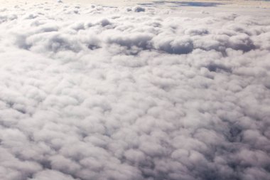 Güzel bulutlar ve gökyüzünden mavi gökyüzü, gökyüzünden ve bulutlardan doğa manzarası. Beyaz bulutlar ve mavi gökyüzü uçak penceresinden cennet gibi görünüyor. Gökyüzündeki güneş ışığı bulutların üzerinde parlar