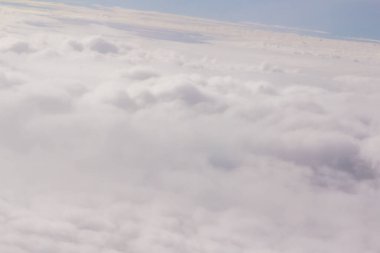 Güzel bulutlar ve gökyüzünden mavi gökyüzü, gökyüzünden ve bulutlardan doğa manzarası. Beyaz bulutlar ve mavi gökyüzü uçak penceresinden cennet gibi görünüyor. Gökyüzündeki güneş ışığı bulutların üzerinde parlar