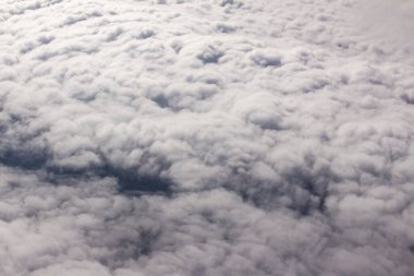Güzel bulutlar ve gökyüzünden mavi gökyüzü, gökyüzünden ve bulutlardan doğa manzarası. Beyaz bulutlar ve mavi gökyüzü uçak penceresinden cennet gibi görünüyor. Gökyüzündeki güneş ışığı bulutların üzerinde parlar