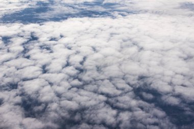 Güzel bulutlar ve gökyüzünden mavi gökyüzü, gökyüzünden ve bulutlardan doğa manzarası. Beyaz bulutlar ve mavi gökyüzü uçak penceresinden cennet gibi görünüyor. Gökyüzündeki güneş ışığı bulutların üzerinde parlar