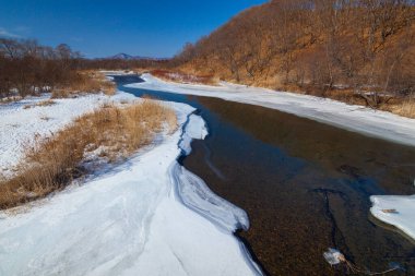 Nehir sonbaharda tepenin arka planında, nehir buzla kaplıdır..