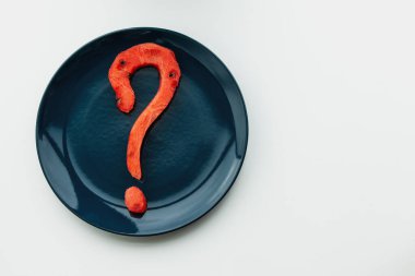 Karpuzdan kesilen bir soru işareti beyaz arka planda mavi bir tabakta yatar..