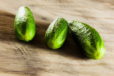 Gri ahşaplı salatalık arka planda, taze sebzeler, bahçede yaz mevsimi..