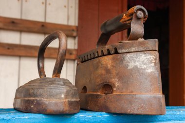 Antika kömür demirleri. Ahşap mavi rafta eski moda ütü aletleri. Miras kavramı..