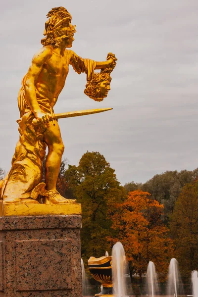 Metal statue of a man with a sword and head in an autumn Park against a background of red leaves.