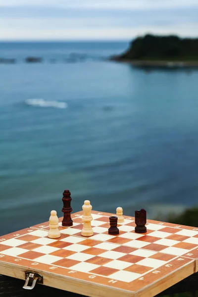 Sahilde satranç oynamak. Güneşli bir günde denizin arka planında ve yarımadada satranç tahtası. Sahilde tatil.