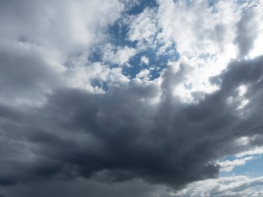 Mavi gökyüzünde dramatik bulutlar. Bulutların arkasındaki güneş, parlak kenarları işaretliyor..