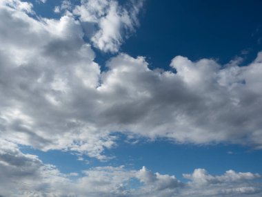 Mavi gökyüzünde dramatik bulutlar. Bulutların arkasındaki güneş, parlak kenarları işaretliyor..