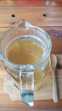 Kahverengi ahşap bir masaya yerleştirilmiş cam bir kavanozdaki yasemin çayının en üst görüntüsü..