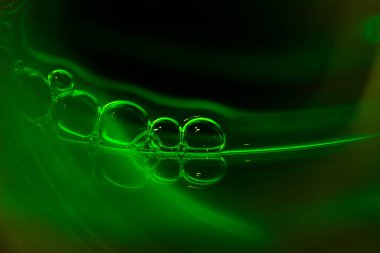 Zengin yeşil neon arka planda sabun köpükleri. Köpüğün şekli ve dokusu. Gradyan yeşil renk. Makro mod.