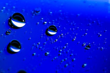 Mavi neon arka plana büyük ve küçük su damlaları düşer. Klasik moda mavi. makro kip.