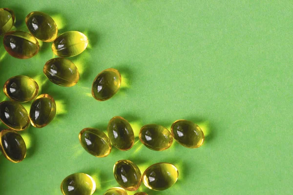 vitamins in capsules are yellow on a green background.close up.the concept of vitamin and mineral deficiency for the health of the body.space for text.the view from the top