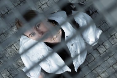 Beyaz ceketli ve sırt çantalı genç bir bayan turist. Yukarıdan ızgaraya bak. Geometrik çizgiler. Röntgencilik efekti.