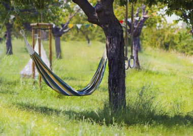 Çizgili bir hamak ve Park 'taki bir ağaçta çocukların spor yüzükleri. Renkli bayraklar ve çocuk çadırı. Güneşli bir yaz gününde temiz havada eğlence ve dinlenme kavramı.