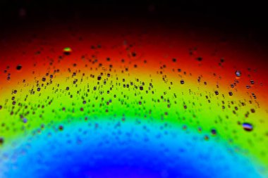 Rainbow.makro kipinin neon renklerinin arka planında küçük su damlaları.