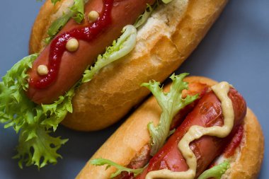 İki ev yapımı klasik sosisli, sarı hardal, ketçap ve taze yeşil salata. Amerikan Fast Food. Ulusal Bayram Sosisli Günü. Kapatın..