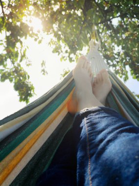 Kirazlı bir ağacın arka planında, güneşin altında çıplak ayaklı bir kadın. Bir insan, hasat veya uzun bir çalışmadan sonra bahçede dinleniyor. Alış veriş merkezinin derinliği. Çevrimdışı yaşam konseptimiz.