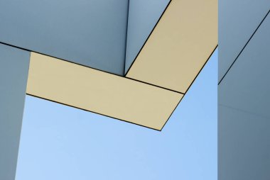 Mavi gökyüzüne karşı geometrik şekilli modern bir binanın bir parçası. Minimalizm tarzında kentsel mimari..