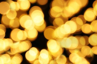 Odaklanamayan sarı ışıklar koyu bir arkaplan üzerine kuruludur. Noel arkaplanı soyut bokeh dokusu. Kutlama ya da parti konsepti.