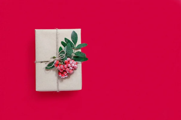 Gift box in craft paper on a red background. The concept of zero waste.Eco-friendly natural decor for packaging Christmas and new year gifts.flat lay.copy space