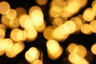 Odaklanamayan sarı ışıklar koyu bir arkaplan üzerine kuruludur. Noel arkaplanı soyut bokeh dokusu. Kutlama ya da parti konsepti.