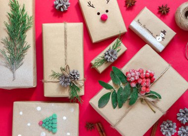 Kırmızı zemin üzerinde el işi kağıdının içinde hediye kutularının Noel kompozisyonu. Sıfır atık kavramı. Noel hediyelerini paketlemek için çevre dostu doğal dekor.