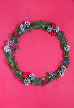 Parlak Noel arkaplanı. Kırmızı bir arkaplanda köknar dalları, koniler, böğürtlenler, anason, tarçın çelengi. Yeni yıl dekor.flat lay.copy space. Dikey yönelim