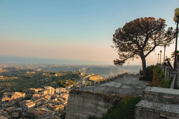 Günbatımında Gerace, Calabria 'nın (İtalya) hava manzarası. Güney İtalya 'da bir köy. Gün batımında Gerace 'in panoramik manzarası, etraflarındaki taş evleri ve odunları görmek mümkün. Köy bir tepede..