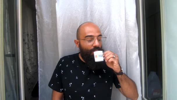 一个年轻的同性恋者在家里的大窗户边 一边喝着印有 爱就是爱 字样的咖啡 一边欣赏着他在家里度过的时光 — 图库视频影像