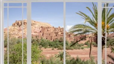 Kuşlar uçarken Ait Ben Haddou şehri beyaz bir pencereden görüldüğü gibi. Kasbah, Fas 'ın Atlas Dağları' nda Ouarzazate yakınlarında görülmektedir. 1987 'den beri UNESCO' nun Dünya Mirası Bölgesi. Kızıl köy.