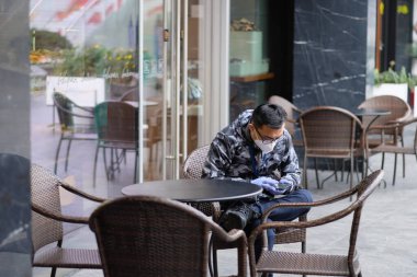 Şangay / Çin-2020: Wuhan 'daki yeni tip Coronavirus COVID-19 pnömonisi Çin' deki birçok şehre yayılıyor. Cerrahi maske ve eldiven takan insanlar Şangay 'da kafenin önünde oturuyorlar.