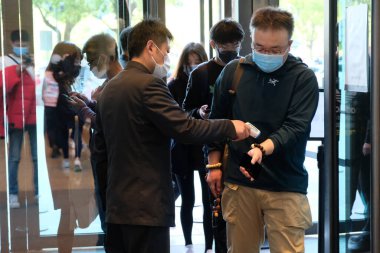 Suzhou / China-April 2020: Coronavirüs 'ü önlemek ve kontrol etmek için, alışveriş merkezi çalışanı müşterilerin giriş noktasındaki sıcaklığını ölçüyor.