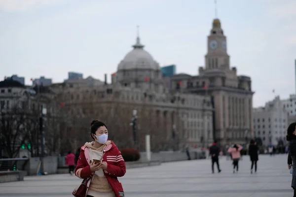 Shanghai / China-March.2020: Coronavirus COVID-19 birçok şehre yayılıyor. Cerrahi maske takan genç bir kadın Şangay 'da yürüyordu.