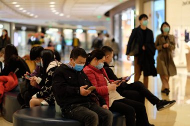 Coronavirus COVID-19 Çin 'de kontrol ediliyor. Alışveriş merkezinde oturan ameliyat maskesi takan bir sürü insan var.. 